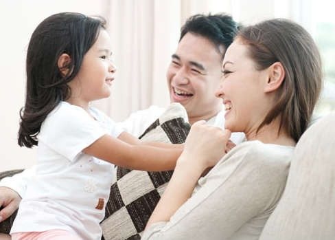 A family laughing together on the couch at home